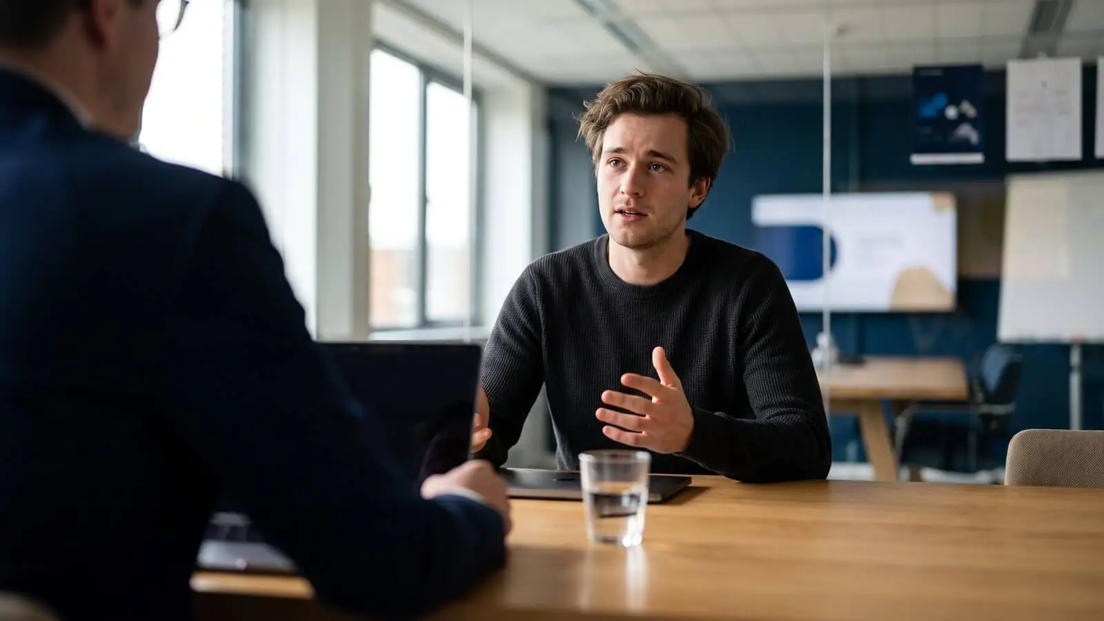 Candidate explaining his work to an interviewer across a meeting room table